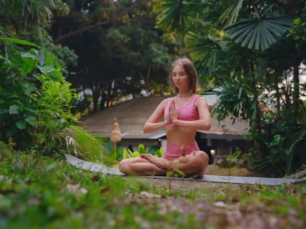 Une femme en pleine méditation au milieu d'un jardin vert