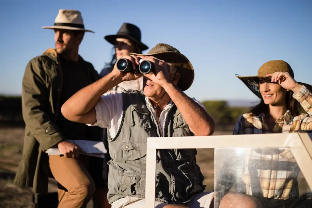 Un groupe de personne en plein safari qui observe la nature depuis un véhicule avec des jumelles