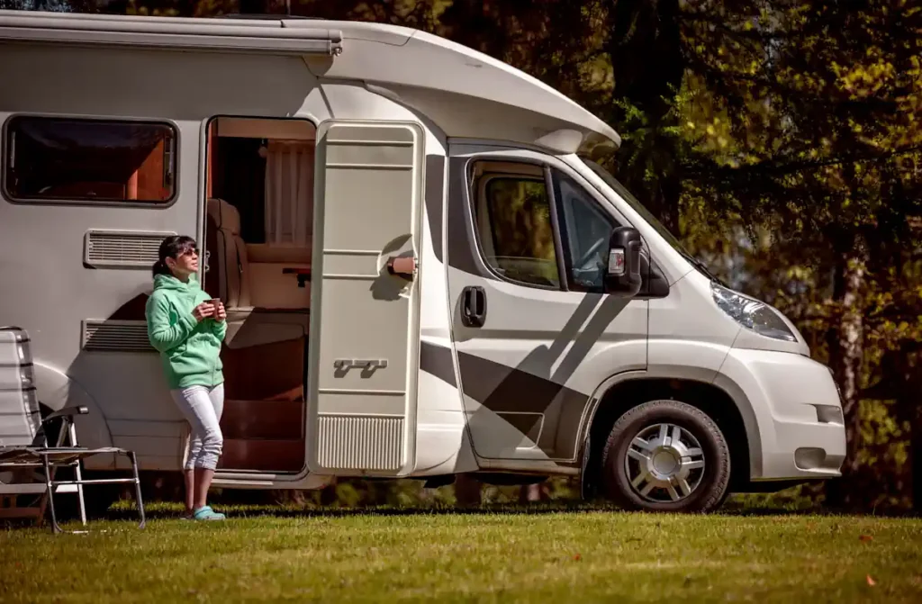 Une femme qui s'appuie contre un camping-car blanc à l'arrêt