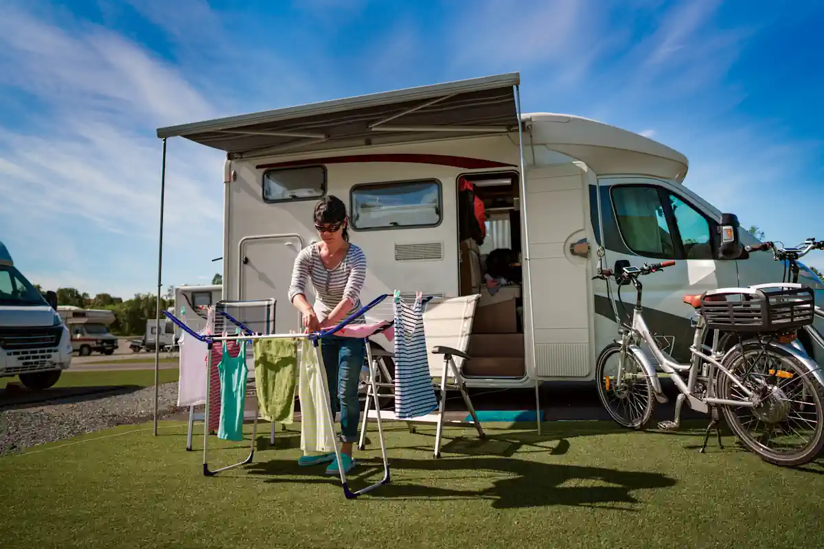 Une femme qui étale son linge devant un camping-car blanc