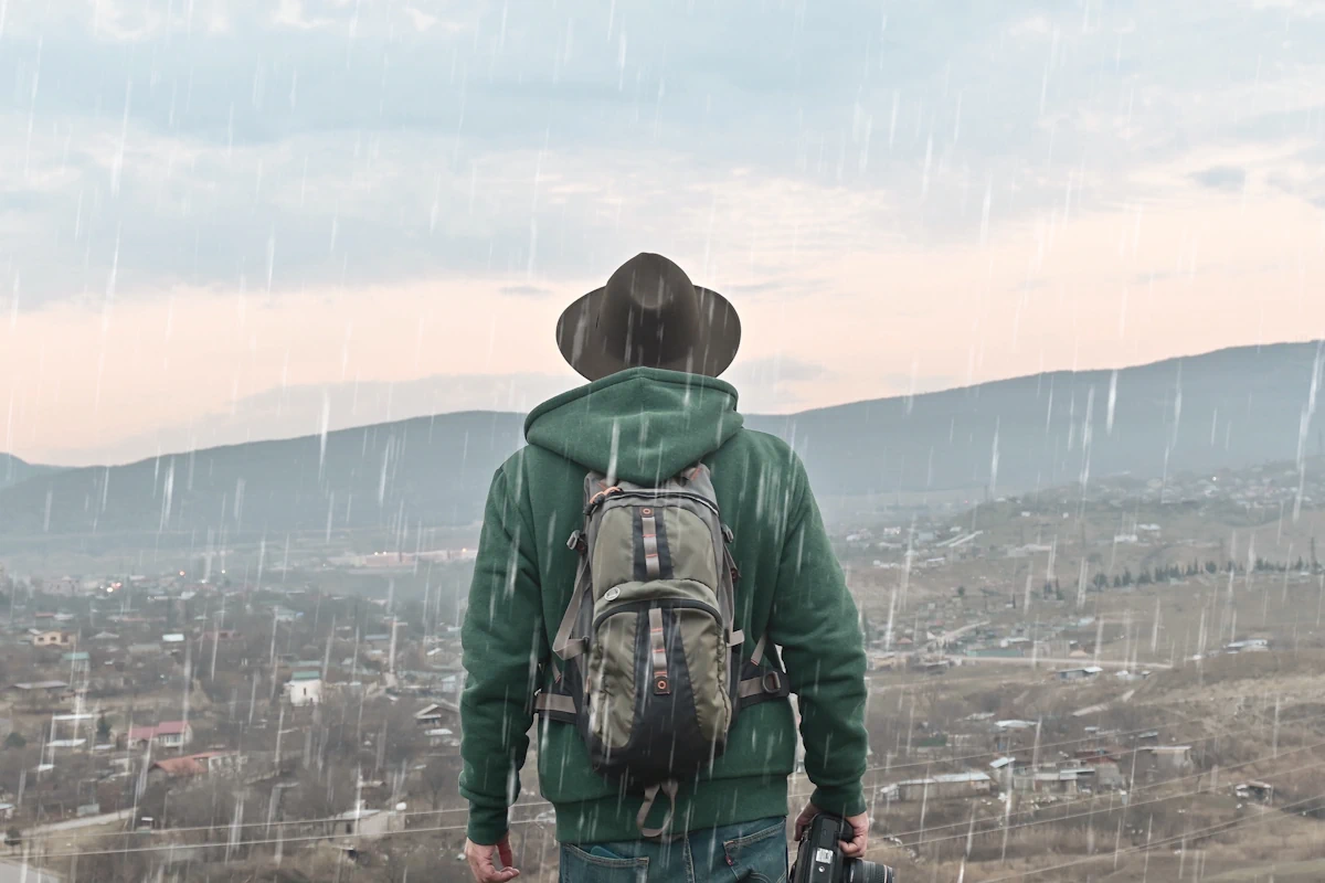 Un homme avec un sac à dos qui marche sous la pluie
