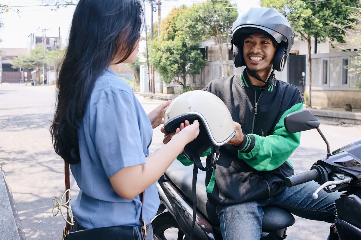 Une femme qui prend un casque tendu par un conducteur de moto