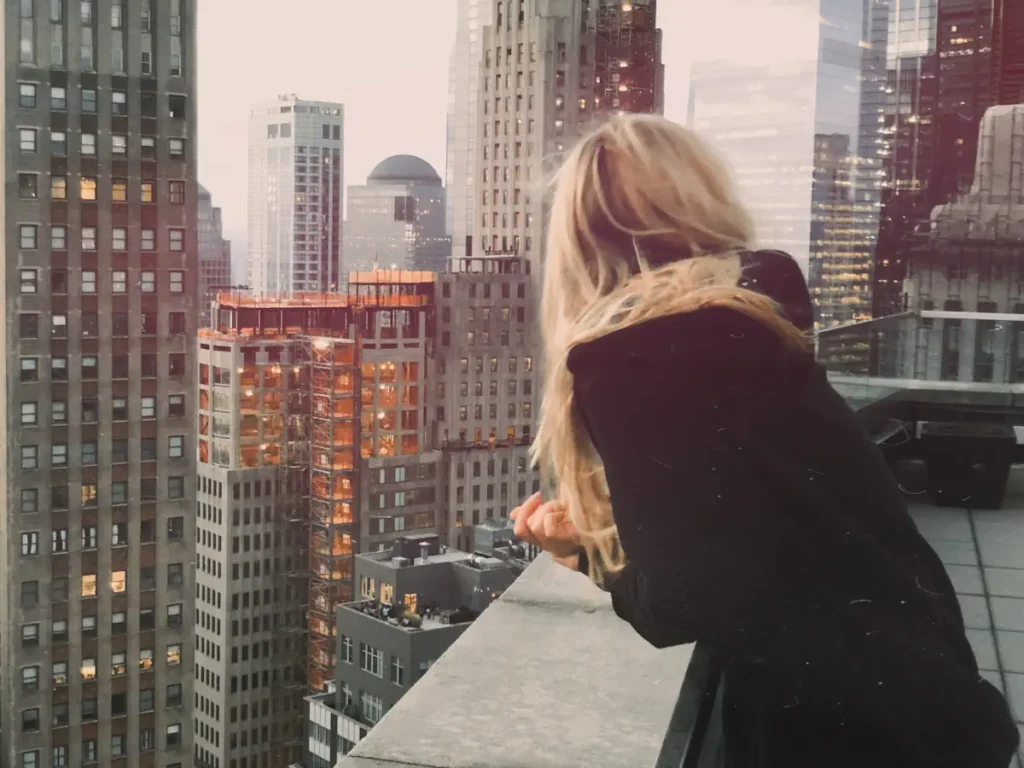Une femme sur un balcon qui regarde les grands immeubles