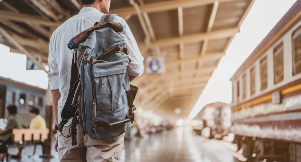 Un homme avec un sac à dos qui attend sur le quais d'une gare
