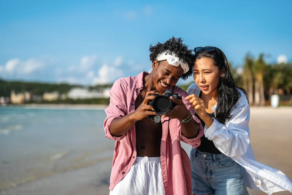 Une femme et un jeune homme qui regarde une photo sur un appareil à la plage
