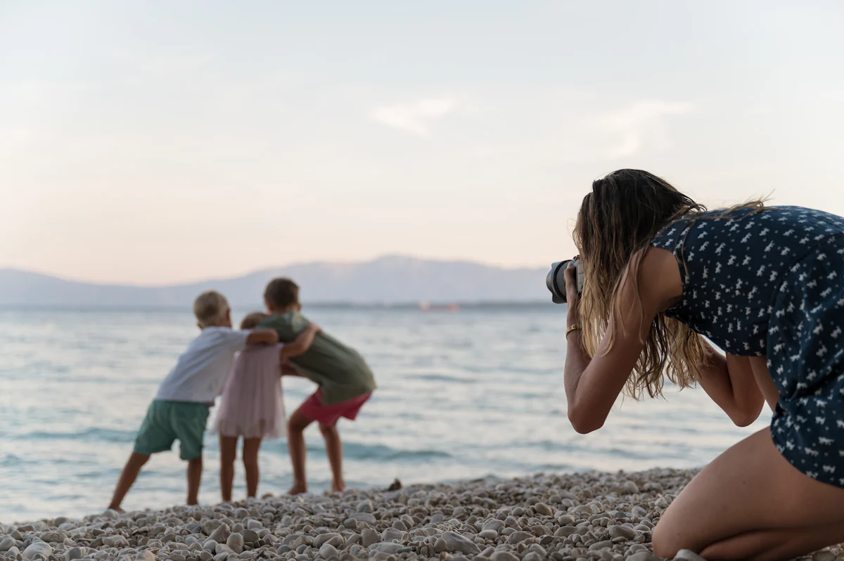 Une femme qui prend en photo des enfants à la plage