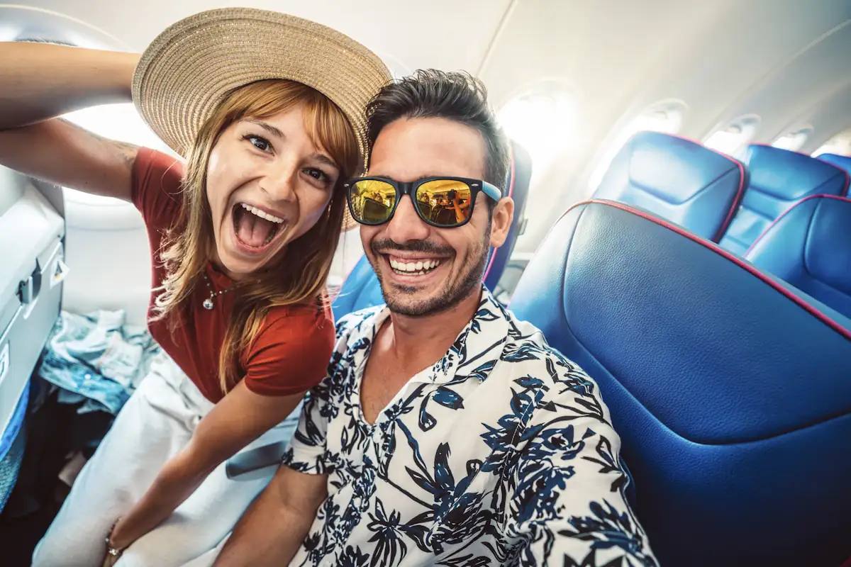 Un couple en tenue décontractée qui se prend en photo dans un avion