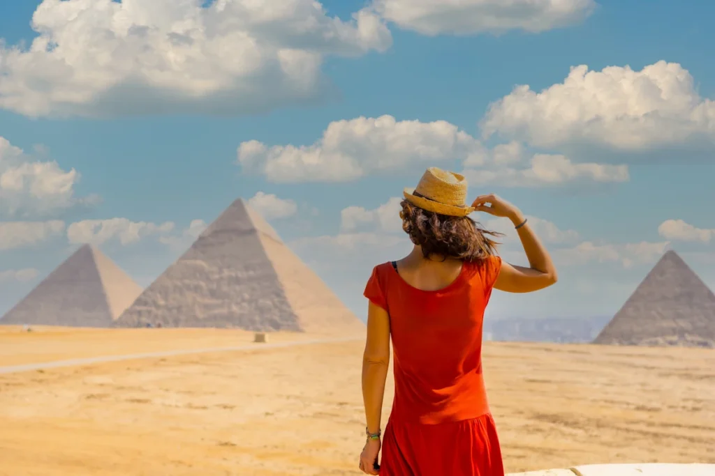 Une femme en robe rouge et chapeau qui visite l'Egypte